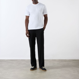 Model wearing Prada white cotton crew neck T-shirt, styled with black wide-leg trousers and dark espadrilles.