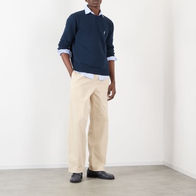 Model wearing Prada sand cotton trousers, styled with a navy knit sweater, light blue shirt, and dark loafers.