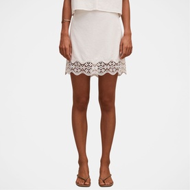 Model wearing Forever New porcelain mini skirt with scalloped broderie anglaise hem, styled with matching top and tan sandals.