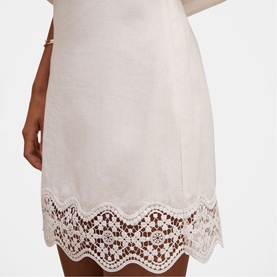 Model wearing Forever New porcelain dress with delicate scalloped lace hem trim detail, styled with a gold bangle bracelet.