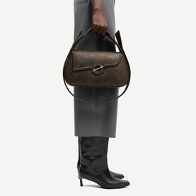Model carrying Samsoe & Samsoe washed gunmetal shoulder bag with silver-tone buckle clasp and top handle, styled with grey trousers and black