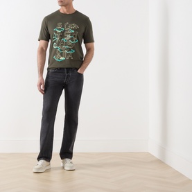 Model wearing Scotch & Soda Forest Night green graphic cotton T-shirt, styled with dark slim jeans and white trainers.