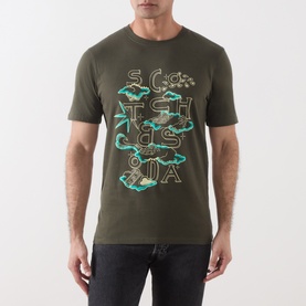 Model wearing Scotch & Soda T-shirt in Forest Night green with multicolour stacked logo graphic print, short sleeves, crew neck.