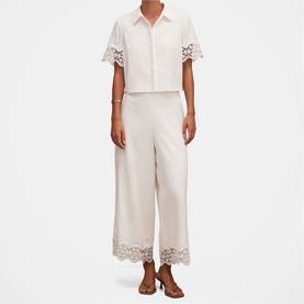 Model wearing cream wide-leg trousers with lace hem trim, styled with matching lace-trim shirt and tan sandals