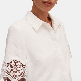 Model wearing white short-sleeve shirt with lace trim detail on sleeves and collar neckline