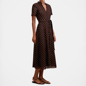 Model wearing brown polka dot midi shirt dress with short sleeves and tie waist, styled with tan flat sandals
