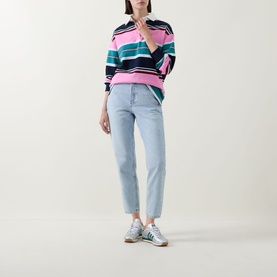 Model wearing Tommy Flag Logo Cropped Mom Jeans in Denim Light, styled with a multicolour striped polo top and white trainers.