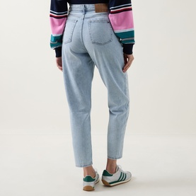 Model wearing Tommy Flag Logo Cropped Mom Jeans in Denim Light, back view, styled with a colour-block sweatshirt and green trainers.