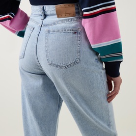 Model wearing Tommy Flag Logo Cropped Mom Jeans in Denim Light, light-wash cotton denim, five-pocket style with brand patch, styled with striped