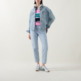 Model wearing Tommy Flag Logo Cropped Mom Jeans in Denim Light, styled with a denim jacket, striped top and green trainers.