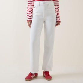 Model wearing Tommy High-Rise Slim Leg Jeans in Denim White, styled with a red striped top and red Adidas trainers.