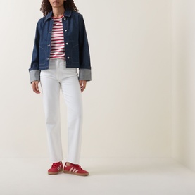 Model wearing Tommy High-Rise Slim Leg Jeans in Denim White, styled with a dark denim jacket, pink striped top and red trainers.