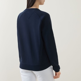 Model wearing Tommy Dark Night Navy cotton sweatshirt, back view, styled with white trousers