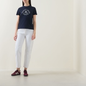 Model wearing Tommy Heritage Logo T-Shirt in Dark Night Navy with white cropped trousers and burgundy trainers.