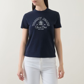 Model wearing Tommy Heritage Logo T-Shirt in Dark Night Navy with white Heritage Sports Club graphic print, styled with white jeans.