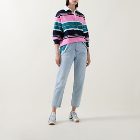 Model wearing Tommy Flag Logo Striped Rugby Top in Pink Daisy Multi Stripe with light blue cropped jeans and white trainers.