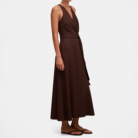 Model wearing dark brown sleeveless wrap midi dress with V-neckline and tie waist, styled with brown strappy flat sandals