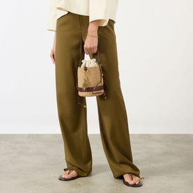 Model carrying Chloe Charm Small Basket Crossbody Bag in Crafty Brown, woven finish with gold-tone hardware and leather trim, styled with olive