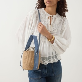 Model carrying Chlo&eacute; Woody Small Basket Bag in Ashes Blue; woven basket body, denim panel, gold-tone hardware, crossbody strap. Styled with white
