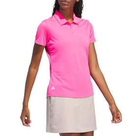 Model wearing Adidas Golf Solar Pink short-sleeve polo shirt, styled with a light grey mini skirt