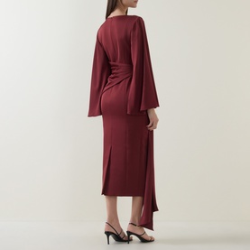 Model wearing Maisonel Draped Pencil Dress in Brick, midi length with flared sleeves, rear vent, styled with black heeled mules.
