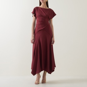 Model wearing Maisonel Gathered Scarf Dress in Brick, featuring short sleeves, gathered waist, and asymmetric hemline, styled with strappy heels.