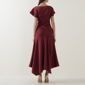 Model wearing Maisonel Gathered Scarf Dress in brick, showing asymmetric hemline, gathered waist detail and short sleeves from the back.