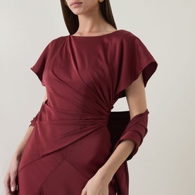 Model wearing Maisonel Gathered Scarf Dress in brick, featuring round neckline, short sleeves and gathered waist detail with asymmetric hemline.