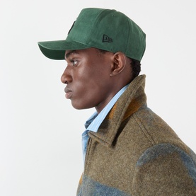 Model with New Era Los Angeles Dodgers Faux Suede 9FORTY E-Frame Baseball Cap in dark green, worn with olive wool coat and blue shirt.