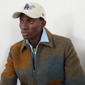 Model with New Era LA Dodgers MLB Food Icon 9FORTY Baseball Cap in beige, styled with a colour-block wool jacket and striped shirt.