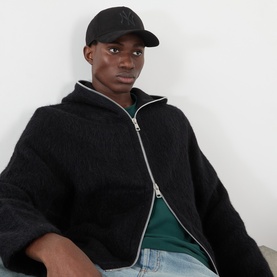 Model with New Era New York Yankees Faux Suede 9FORTY E-Frame Baseball Cap in black, styled with dark zip-up hoodie and green top.