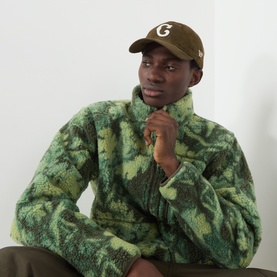 Model with New Era Chicago Cubs Logo MLB Suede Cap in brown, styled with green camo fleece half-zip and brown trousers