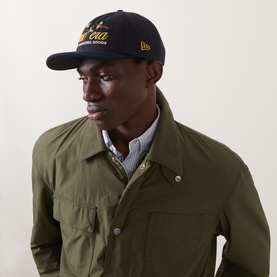 Model with New Era Suede Retro Crown 9FIFTY Baseball Cap in navy, flat visor, embroidered logo, styled with olive overshirt
