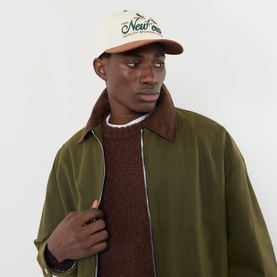 Model with New Era Suede Retro Crown 9FIFTY Baseball Cap in tan, featuring embroidered logo, styled with olive jacket and brown knit