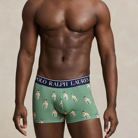 Model wearing Polo Ralph Lauren green trunks with all-over polo bear print and navy branded waistband