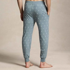 Model wearing grey-blue joggers with allover small pony print, ribbed cuffs, and elasticated waistband, shown from behind.