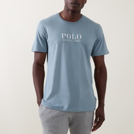 Model wearing Ralph Lauren Script Logo Jersey Sleep Shirt in cool grey blue, with white chest logo print, paired with grey joggers.