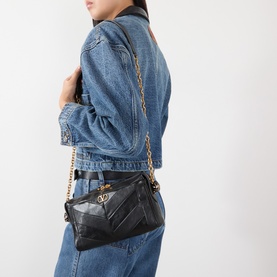 Model carrying Valentino Panthea Suede Shoulder Bag in Nero with gold-tone chain strap and chevron design, styled with denim jacket