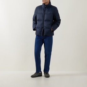 Model wearing Calvin Klein Logo Badge Padded Jacket in Dark Sapphire, styled with matching navy trousers and dark trainers.