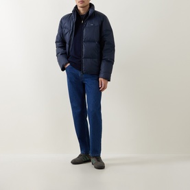 Model wearing Calvin Klein Logo Badge Padded Jacket in Dark Sapphire, styled with blue jeans and grey trainers