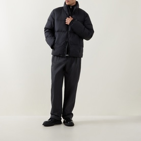 Model wearing Calvin Klein Logo Badge Padded Jacket in black with stand collar, styled with dark trousers and black shoes.
