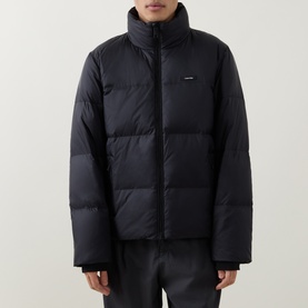 Model wearing Calvin Klein Logo Badge Padded Jacket in black, with stand collar, quilted design and two-way front zip fastening.
