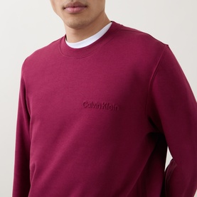 Model wearing Calvin Klein 350 Logo Sweatshirt in Rhododendron, crew neck with tonal embossed chest logo, styled over white tee.