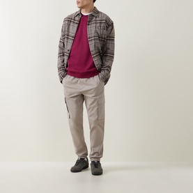 Model wearing Calvin Klein 350 Logo Sweatshirt in Rhododendron, styled with grey plaid overshirt, beige cargo trousers and grey trainers.