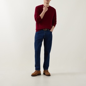 Model wearing Calvin Klein Monogram Logo Knitted Sweater in Rhododendron red, styled with dark blue jeans, black belt and tan suede shoes