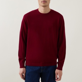 Model wearing Calvin Klein Monogram Logo Knitted Sweater in Rhododendron, crew neck, long sleeves, styled with blue jeans.