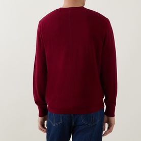 Model wearing Calvin Klein Monogram Logo Knitted Sweater in Rhododendron, crew neck, long sleeves, ribbed trims, styled with blue jeans. Back view.