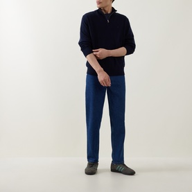 Model wearing Calvin Klein Monogram Logo Half-Zip Sweater in Dark Sapphire, styled with blue trousers and grey trainers.