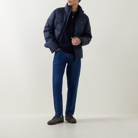 Model wearing Calvin Klein Monogram Logo Half-Zip Sweater in Dark Sapphire, styled with a navy puffer jacket and blue jeans.