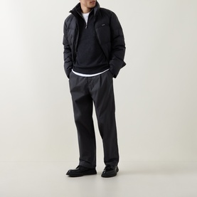 Model wearing Calvin Klein Monogram Logo Half-Zip Sweater in Gunmetal Heather with dark tailored trousers and black loafers.
